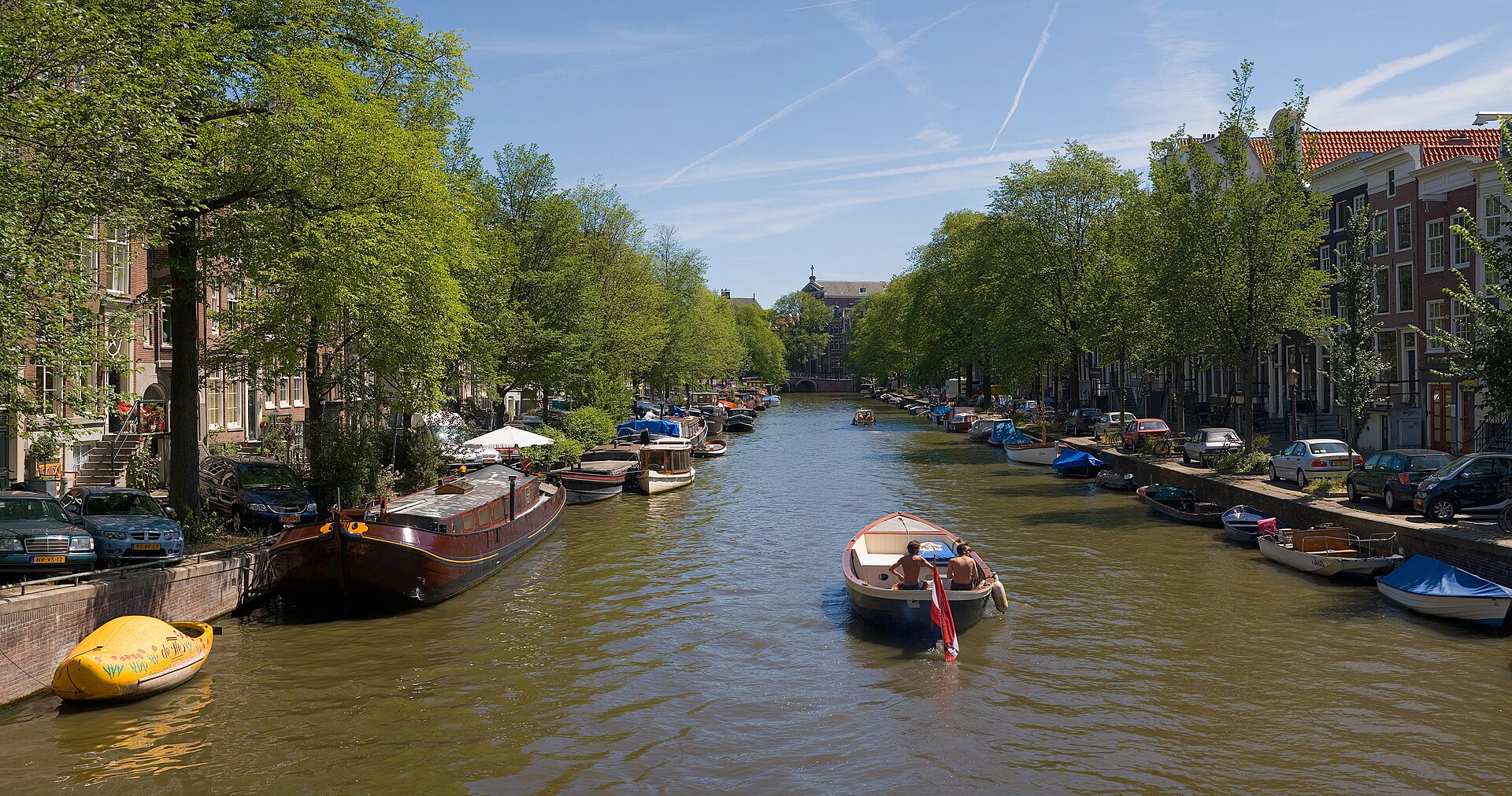 Kanal med husbåtar och små båtar i Amsterdam